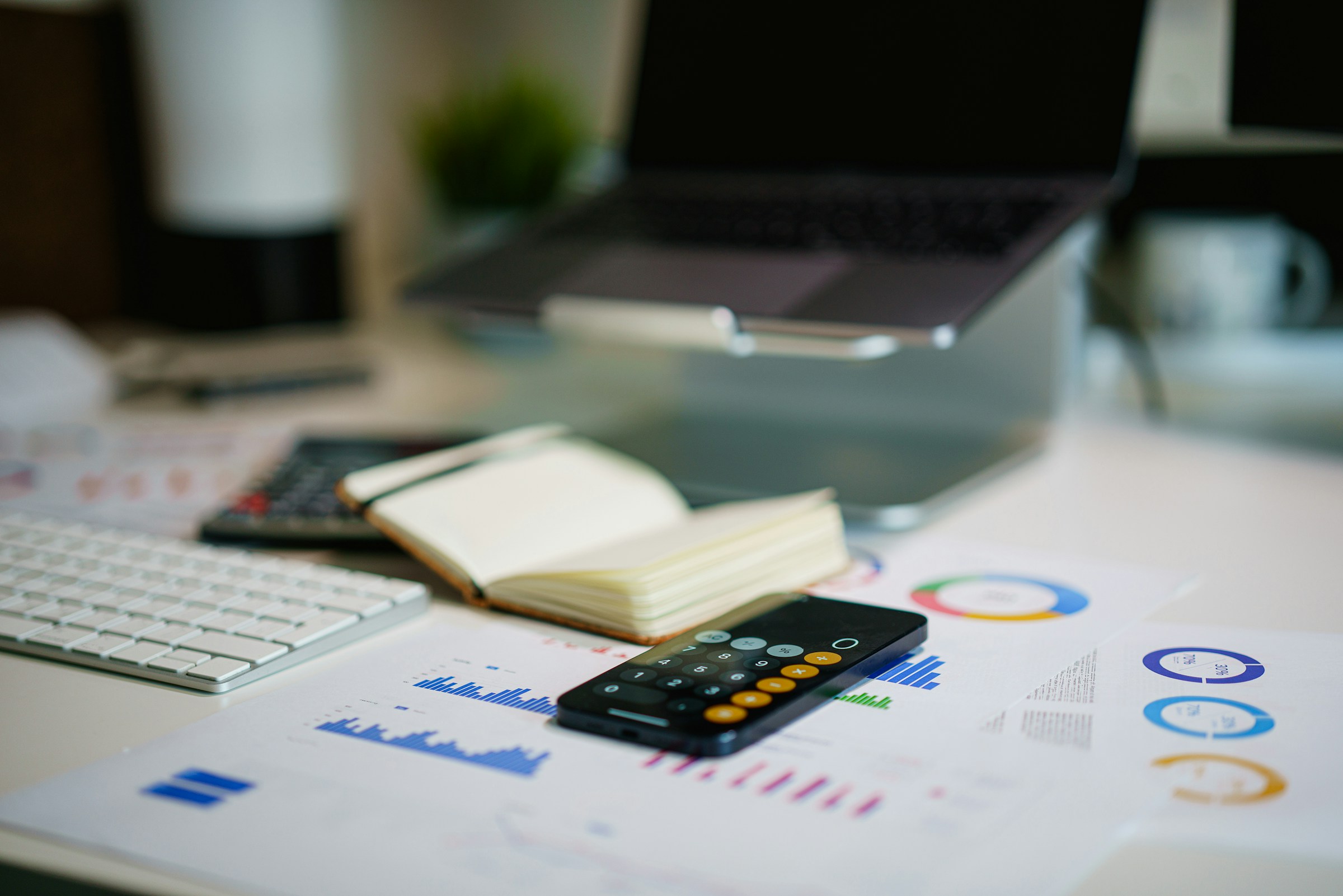 Financial charts, notebook and calculator arranged on an analysis desk